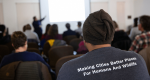 Man wearing a shirt that reads "Making Cities Better Places For Humans And Wildlife" while attending the Urban Wildlife Information Network summit