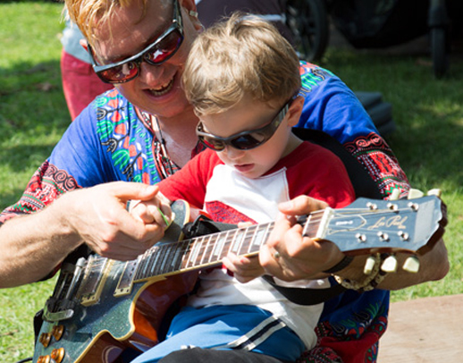 Mr. Singer teaches a child to play the guitar