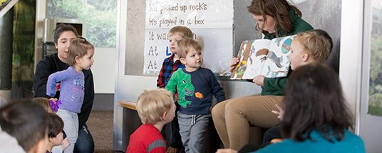 A zoo educator reads a book to children