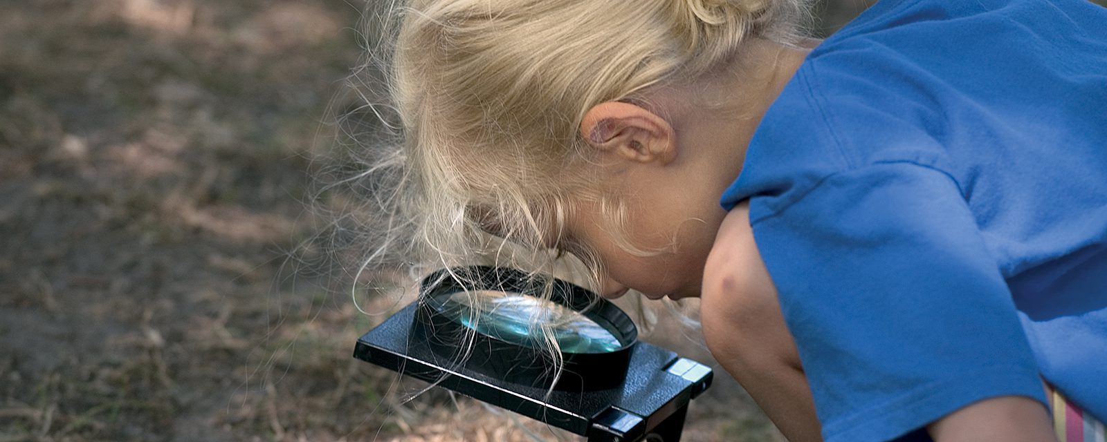 A child peers through a magnifying glass