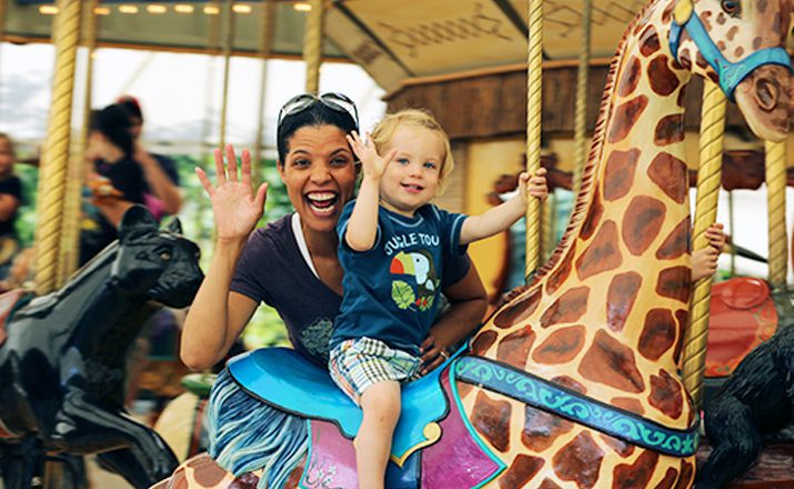 Adult and child riding AT&T Endangered Species Carousel